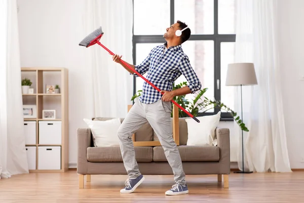 Man met bezem reiniging en plezier thuis — Stockfoto