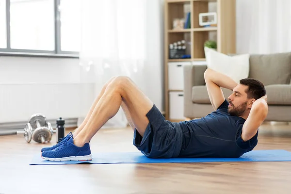 Homem fazendo exercícios abdominais em casa — Fotografia de Stock