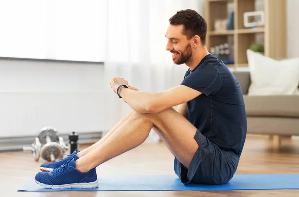 Hombre sonriente con rastreador de fitness haciendo ejercicio en casa —  Fotos de Stock