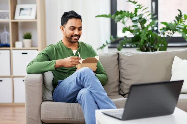 Indio hombre con portátil comer comida para llevar en casa — Foto de Stock