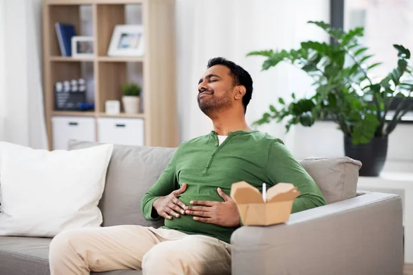 Hombre indio complacido comiendo comida para llevar en casa —  Fotos de Stock