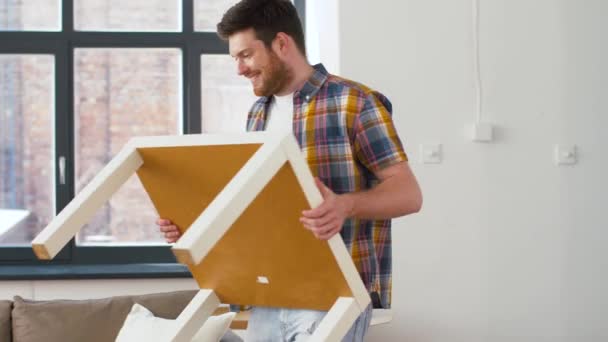 Щасливий чоловік зі столом і коробкою переїжджає в новий будинок — стокове відео