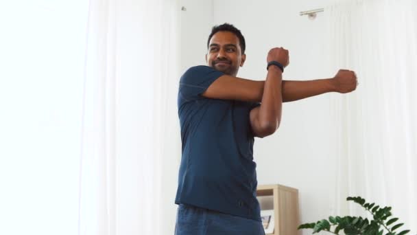 Чоловік з фітнес-трекером розтягує тіло вдома — стокове відео