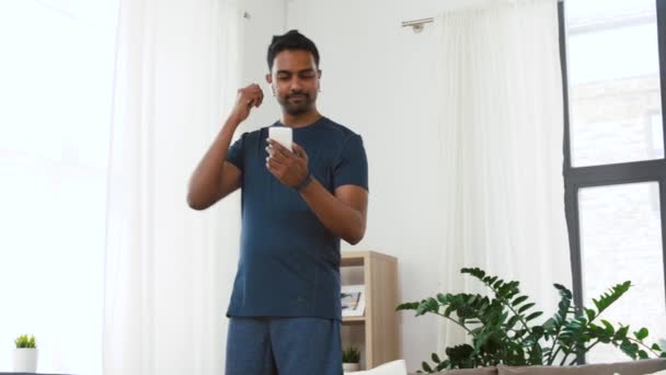 自宅で運動するワイヤレスイヤホンを持つ男 — ストック動画