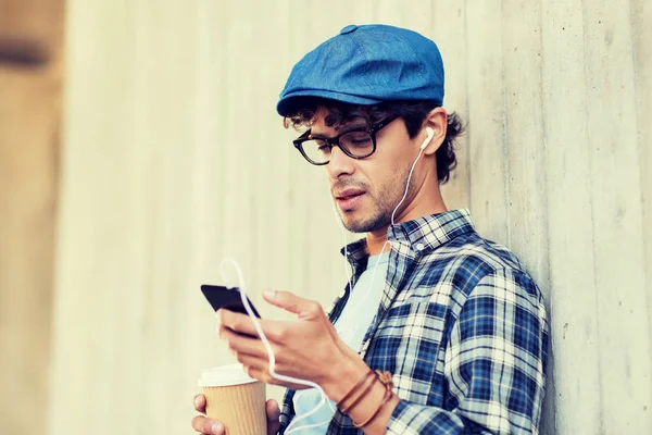 Hombre con auriculares y teléfono inteligente beber café — Foto de Stock