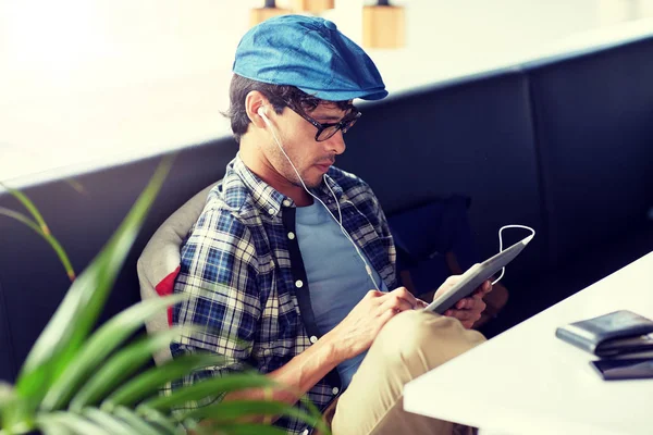 Człowiek z komputera typu tablet i słuchawki, siedząc w kawiarni — Zdjęcie stockowe