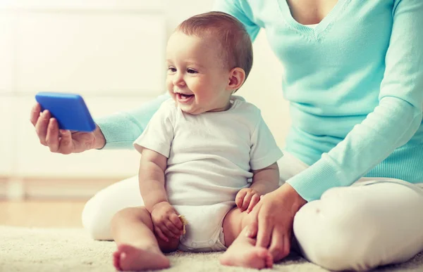 Happy mother showing smartphone to baby at home — Stock Photo, Image