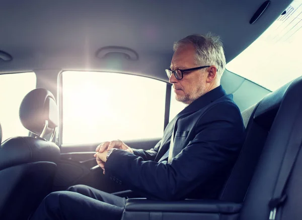 Hombre de negocios senior conduciendo en el asiento trasero del coche —  Fotos de Stock