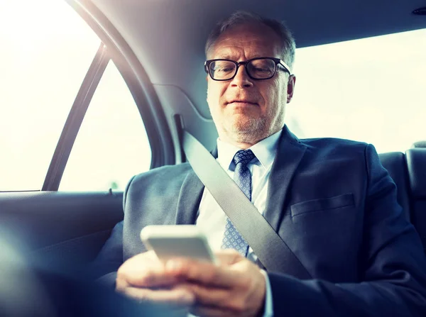 Senior businessman sms su smartphone in auto — Foto Stock