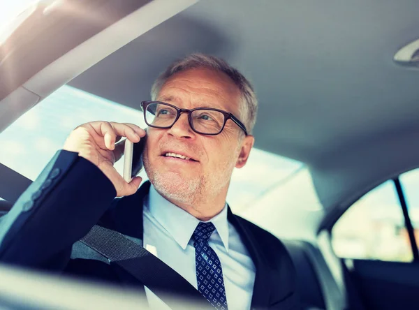 Starszy biznesmen dzwoni na smartfona w samochodzie — Zdjęcie stockowe