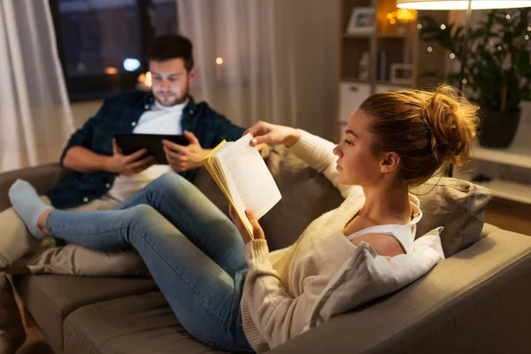 Casal com computador tablet e livro em casa — Fotografia de Stock