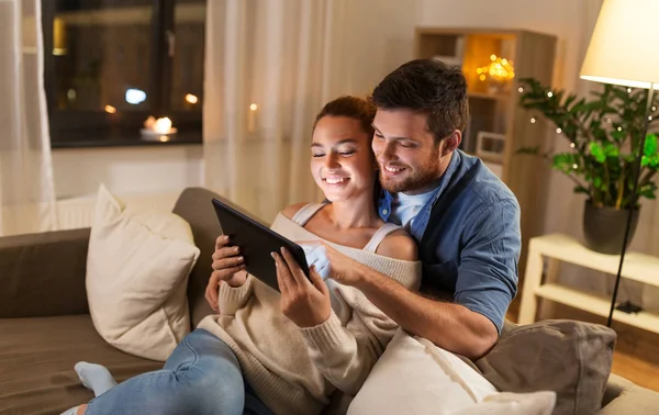 Happy couple using tablet pc at home in evening — Stock Photo, Image