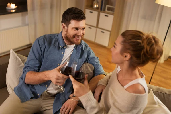 Ευτυχισμένο ζευγάρι πόσιμο κόκκινο κρασί στο σπίτι το βράδυ — Φωτογραφία Αρχείου