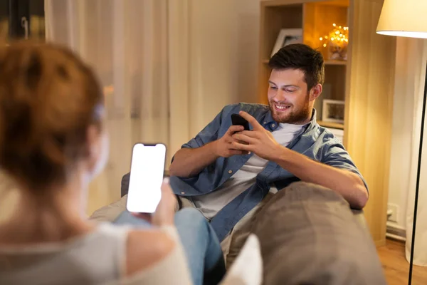 Couple avec smartphones à la maison le soir — Photo