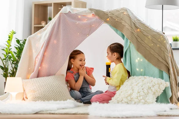 Girls playing with torch in kids tent at home — Stock Photo, Image