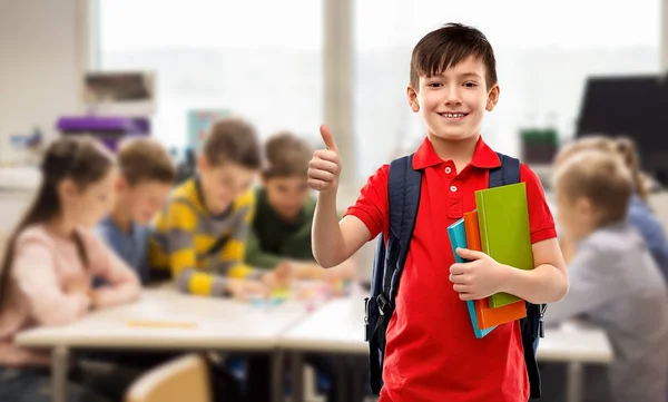 Student jongen met boeken en tas tonen duimen omhoog — Stockfoto