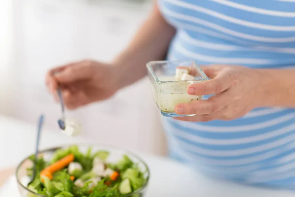 Беременная женщина готовит салат дома — стоковое фото