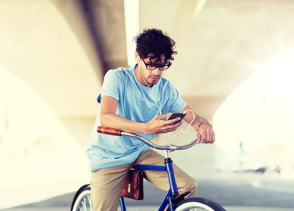 Hombre con smartphone y auriculares en bicicleta —  Fotos de Stock