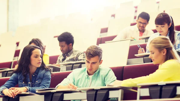 Grupp studenter med anteckningsböcker i föreläsningssalen — Stockfoto