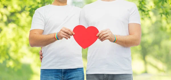 Couple with gay pride rainbow wristbands and heart — Stock Photo, Image