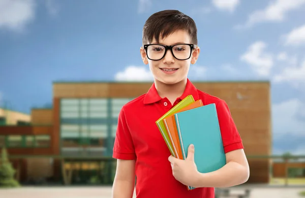 Улыбающийся школьник в очках с книгами — стоковое фото