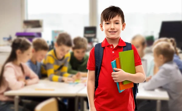 Усміхнений студентський хлопчик з книгами та шкільною сумкою — стокове фото