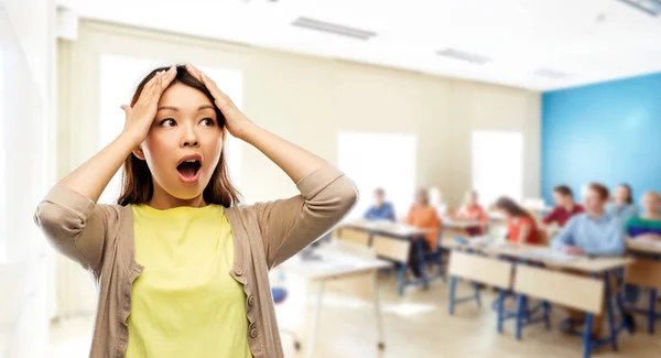 Gestresste Asiatin hält sich in der Schule an den Kopf — Stockfoto