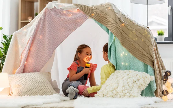 Ragazze che giocano con la torcia nella tenda dei bambini a casa — Foto Stock