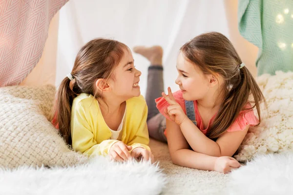 Chicas felices tumbadas en la tienda de los niños y hablando en casa —  Fotos de Stock