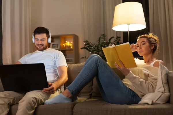 Par med bärbar dator och bok hemma — Stockfoto