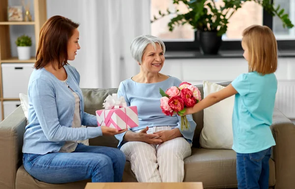 Granddaughter giving flowers to grandmother — Stock Photo, Image