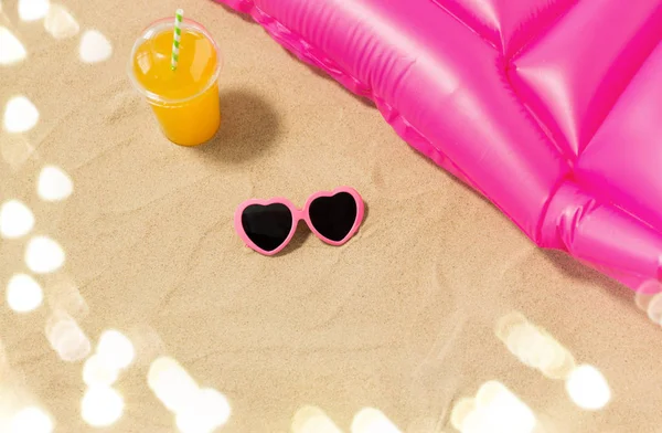 Lunettes de soleil, jus et matelas de piscine sur sable de plage — Photo