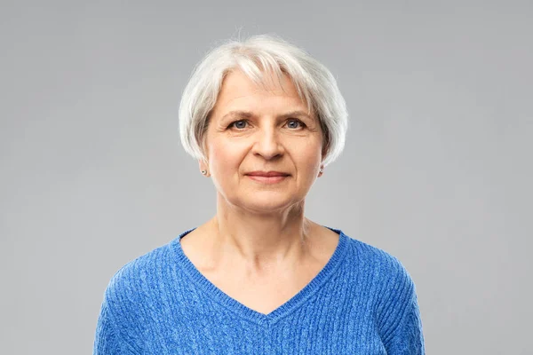 Retrato de mulher sênior em camisola azul sobre cinza — Fotografia de Stock