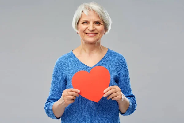 Donna anziana sorridente con cuore rosso — Foto Stock