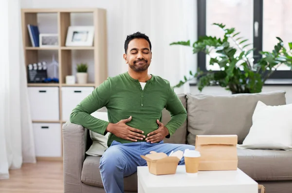 Hombre indio complacido comiendo comida para llevar en casa —  Fotos de Stock