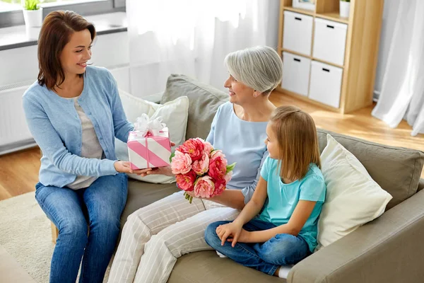 Büyükanneye hediye ve çiçek veren aile — Stok fotoğraf