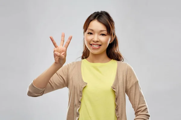 Lachende Aziatische vrouw toont drie vingers — Stockfoto