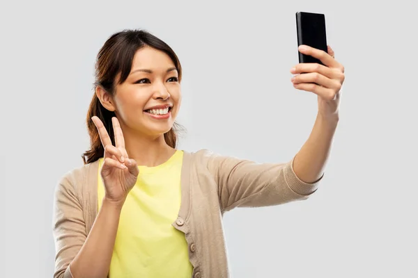 Азиатская женщина делает селфи на смартфоне — стоковое фото