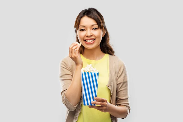 Улыбающаяся азиатская женщина ест попкорн — стоковое фото