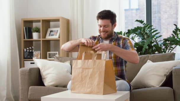 Sorrindo homem desembalando comida takeaway em casa — Vídeo de Stock