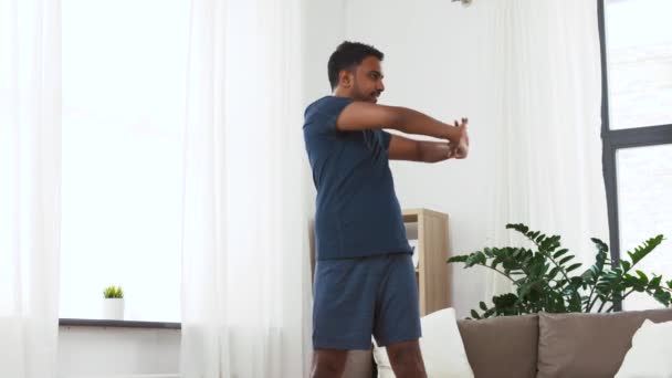 Homme avec tracker fitness étirant la taille à la maison — Video