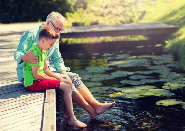 Grand-père et petit-fils assis sur le quai de la rivière — Photo