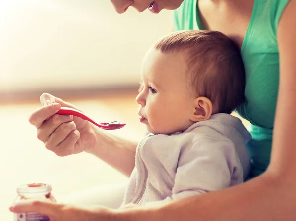 Mother with spoon feeding little baby at home — Stock Photo, Image