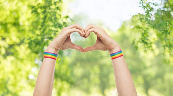 Masculino mãos com gay orgulho pulseiras mostrando coração — Fotografia de Stock