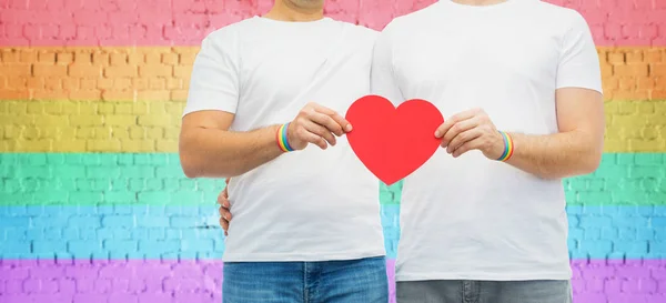 Echtpaar met gay pride regenboog polsbandjes en hart — Stockfoto