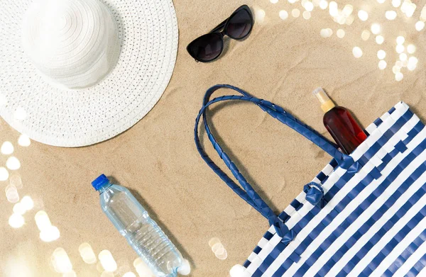 Bolsa de playa, protector solar, gafas de sol y sombrero en la arena —  Fotos de Stock