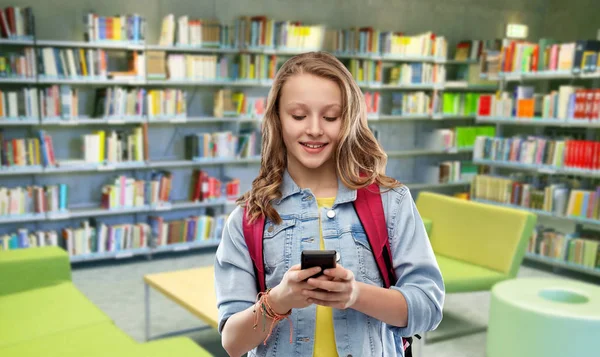 Студентка-підліток з смартфоном у бібліотеці — стокове фото