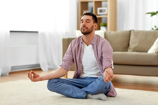 Hombre meditando en la pose de loto en casa —  Fotos de Stock