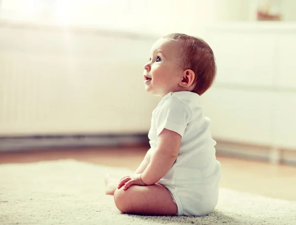 Счастливый мальчик или девочка, сидящие на полу дома — стоковое фото