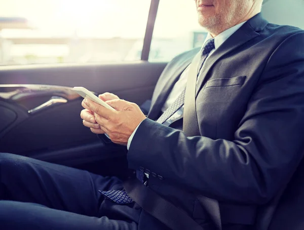 Senior businessman sms su smartphone in auto — Foto Stock